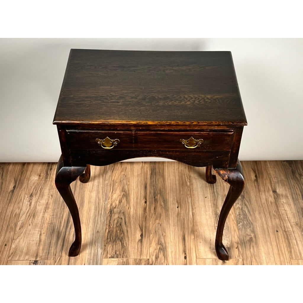 An Antique Queen Anne Style George III Oak One Drawer Stand (late 18th century), featuring curved legs and a front drawer, sits on a wooden floor against a plain light background. Brand: Unknown.