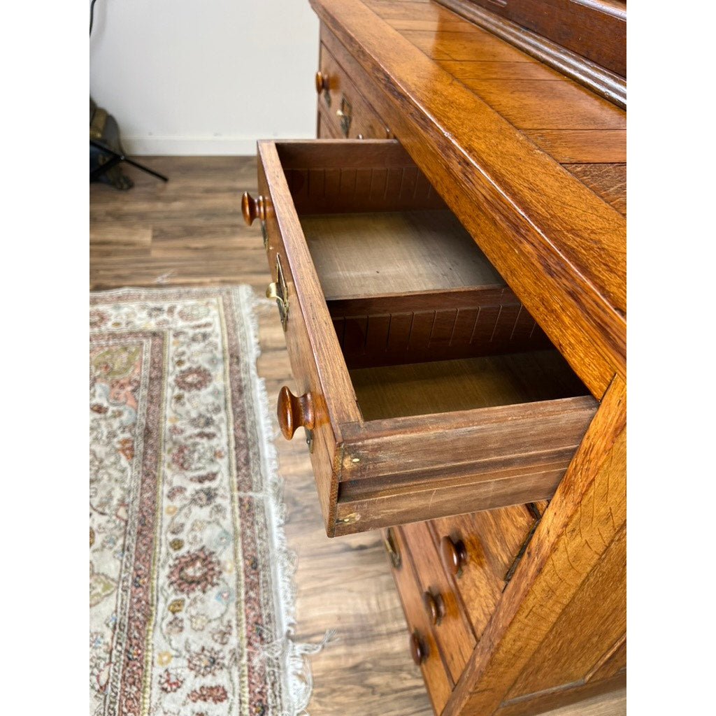 An Antique Early 20th Century Oak Multidrawer File with Roll Top Pigeon Hole Top stands open, revealing its empty interior. A patterned rug and wooden floor beside it highlight its classic, timeless oak design. Brand: None/Unknown.