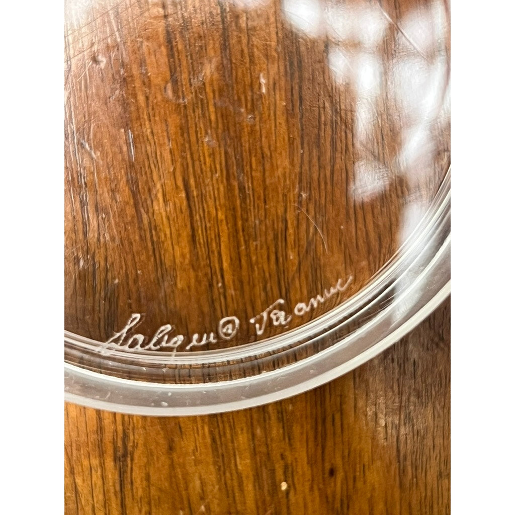 A close-up of a Vintage Lalique France Ballerina Frosted Crystal Covered Powder Box on wood, highlighting the etched Lalique © France signature near the rim.
