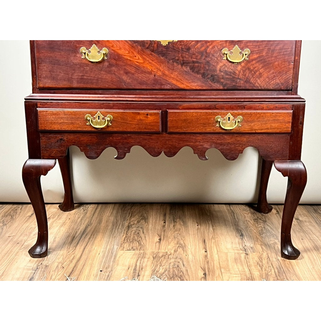 A close-up of the lower half of an Antique Queen Anne Walnut Chest on Frame with drake feet, ornate brass handles, and scalloped apron, probably Irish c. late 18th century, set against a light wall and wood floor.