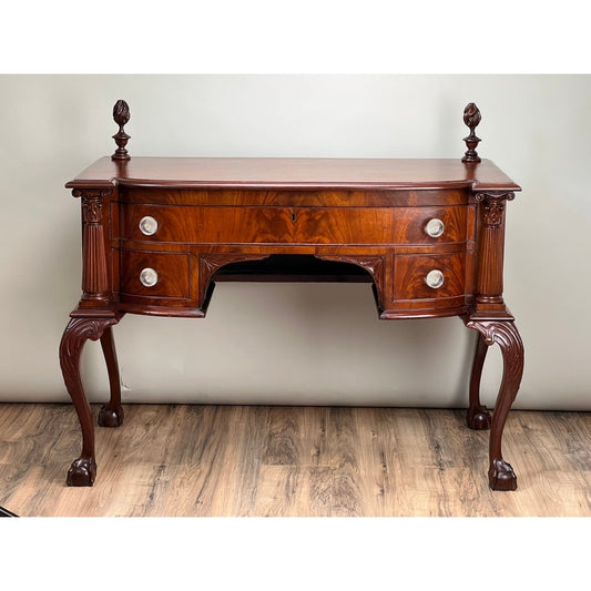Antique George IV Chippendale Flame Mahogany Buffet by Pearl City Antiques, c. Mid 19th Century, featuring elaborately carved legs, four drawers with round metal knobs, and decorative finials accenting both back corners. Set on a wooden floor against a plain light wall, this timeless piece exemplifies classic elegance and exceptional craftsmanship.