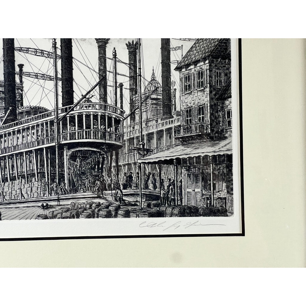 The framed etching “Steamboat Robert E. Lee” by Alan Jay Gaines is a detailed black-and-white artwork showing a busy industrial scene with historic buildings, people, and smokestacks. Signed in pencil at the bottom right corner.