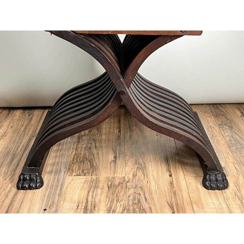 An Antique Italian Renaissance Walnut Savonarola Chair (late 19th century) with X-shaped, slatted legs and carved animal paw feet is displayed on a wood floor against a pale wall. Brand: Unknown.