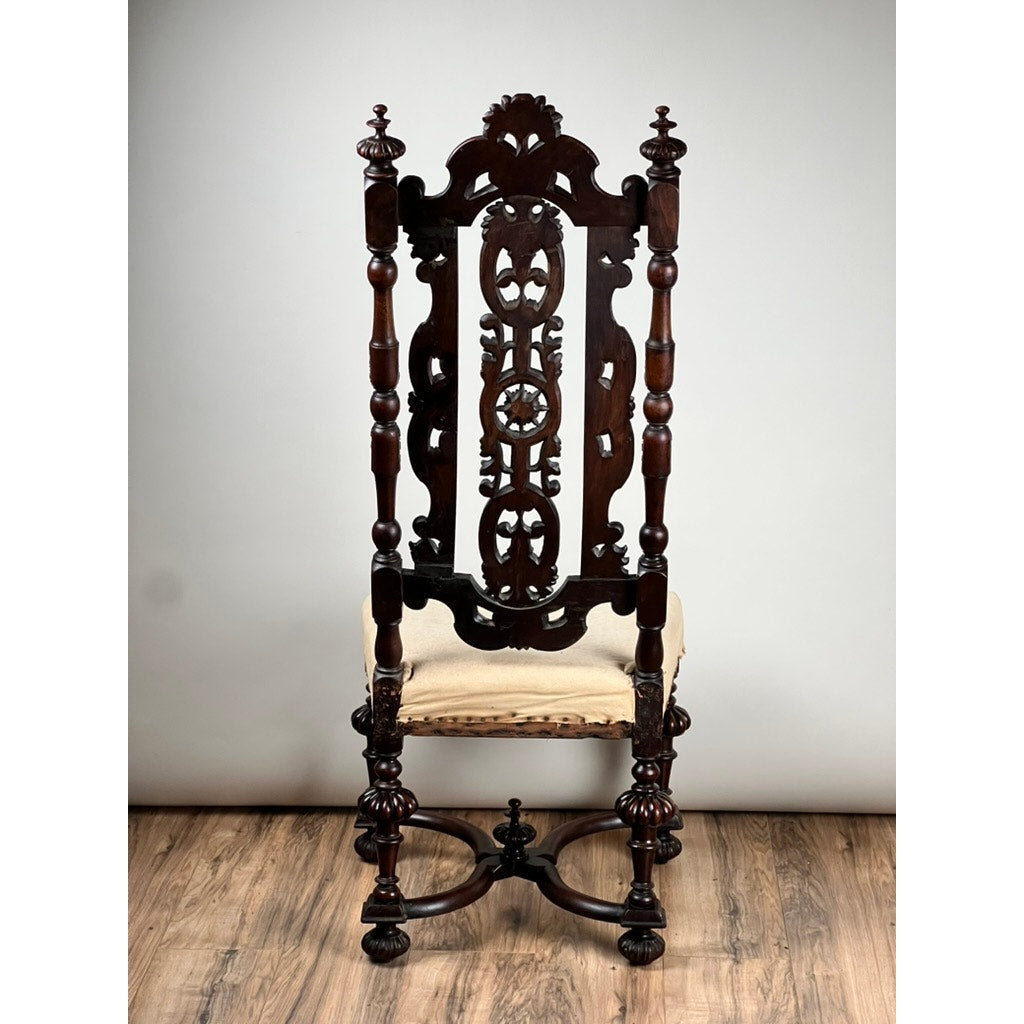 An Antique Fine Carved Flemish Side Chair, attributed to Daniel Marot (late 17th century), features ornate dark wood, a high intricately carved back, turned legs, and a cream upholstered seat on a wooden floor against a plain light background.