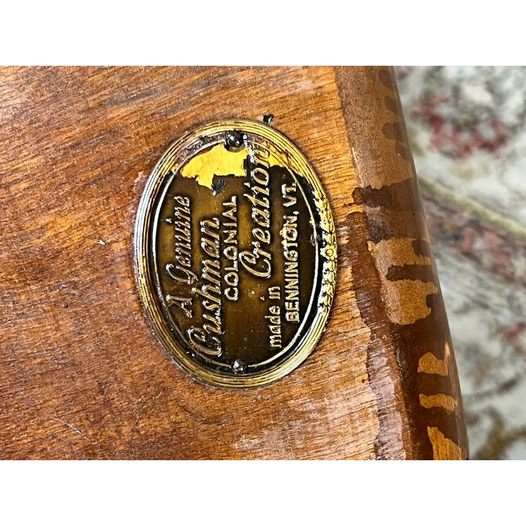 A close-up of the brass plaque on wood reads, A Genuine Cushman Colonial Creation made in Bennington, VT, with some wear—classic signs of a Vintage Herman DeVries for Cushman No. 5-82 Rock Maple Easy Chair.