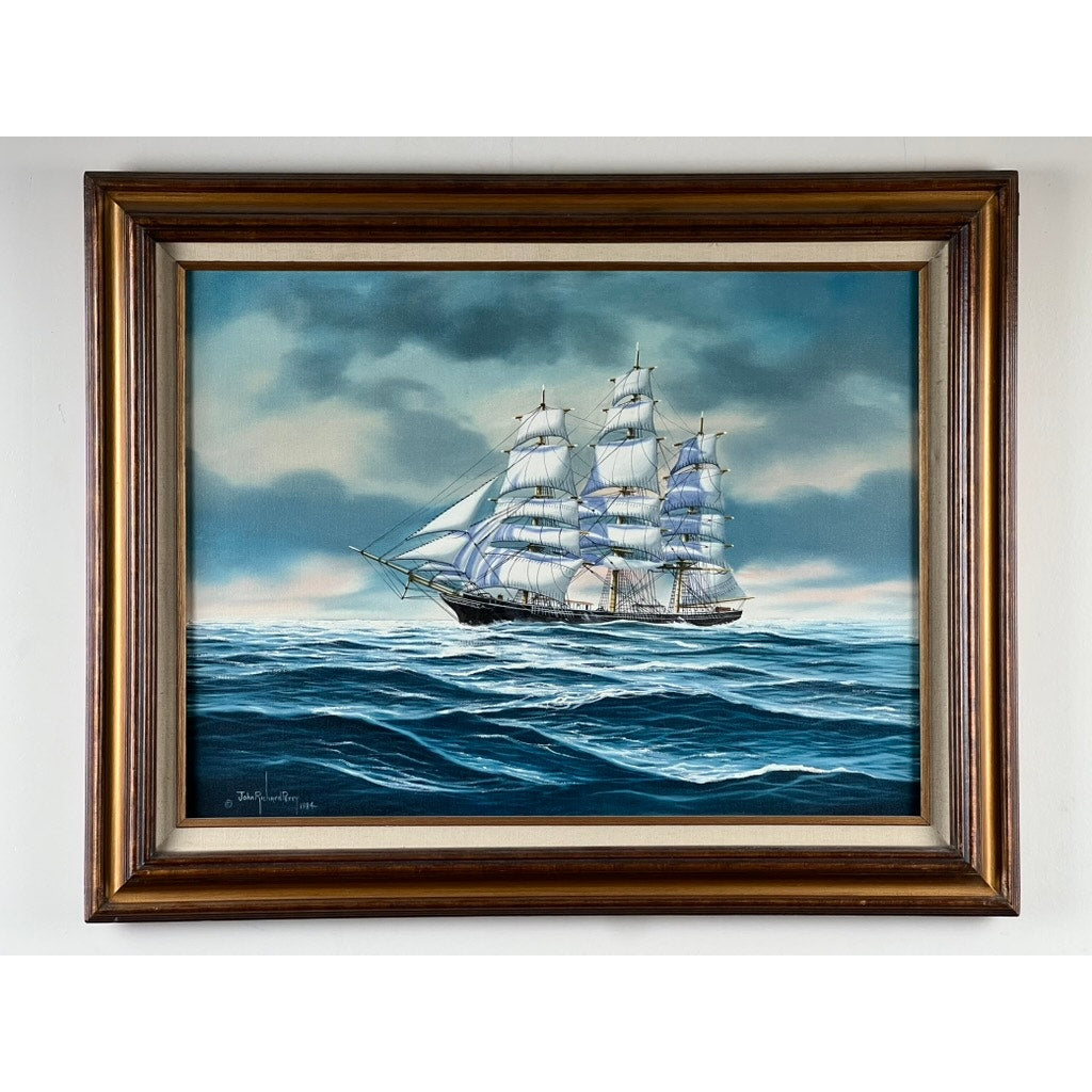 “Tall Ship Under Sail” Oil on Canvas by John Richard Perry ME 1984—a framed painting of a large sailing vessel with white sails on blue waves, under a partly cloudy sky, signed by the artist in the lower left.