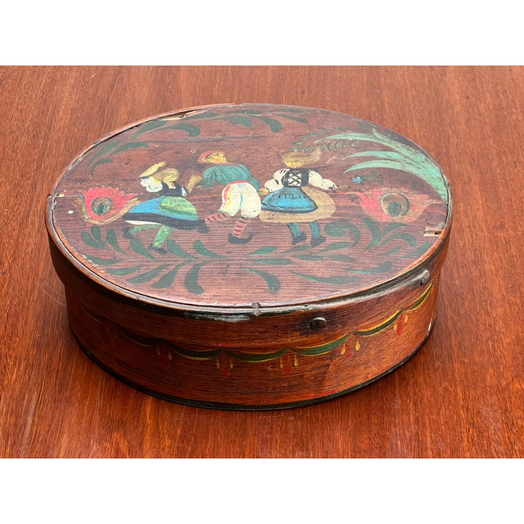 Antique German polychrome painted bentwood "Spanschachtel" ribbon box, late 18th century, features an oval shape with a lid depicting three people in traditional folk dress dancing amid floral and leaf motifs—a classic example of European folk art.