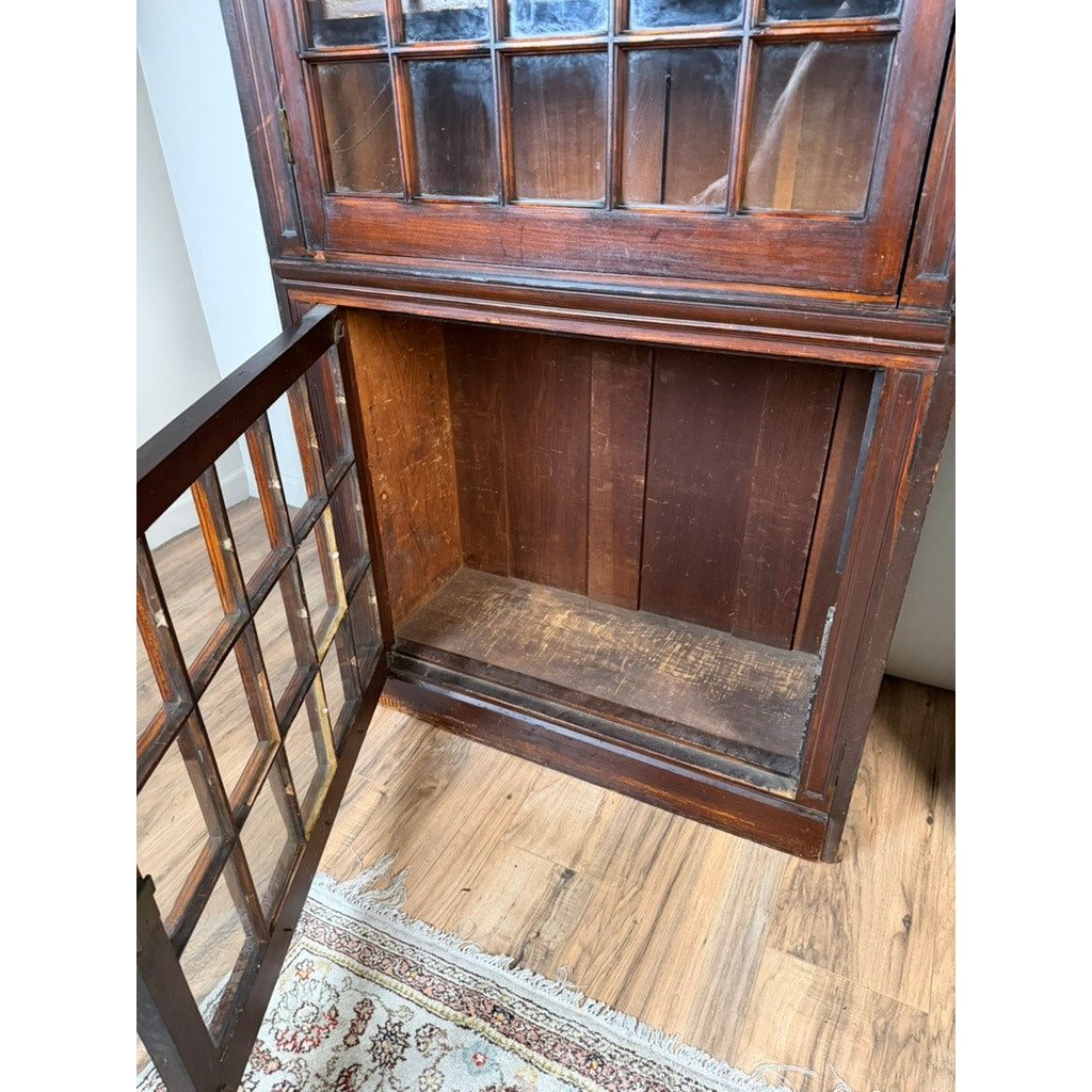 A Pair of Mid-19th Century New England Cherry Glazed Display Cupboards by Pearl City Antiques, dating from around 1840–1860, stands open to reveal an empty interior. The cherry cupboards, featuring glass-paneled doors reminiscent of early American design, are positioned on a wood floor beside a patterned rug.