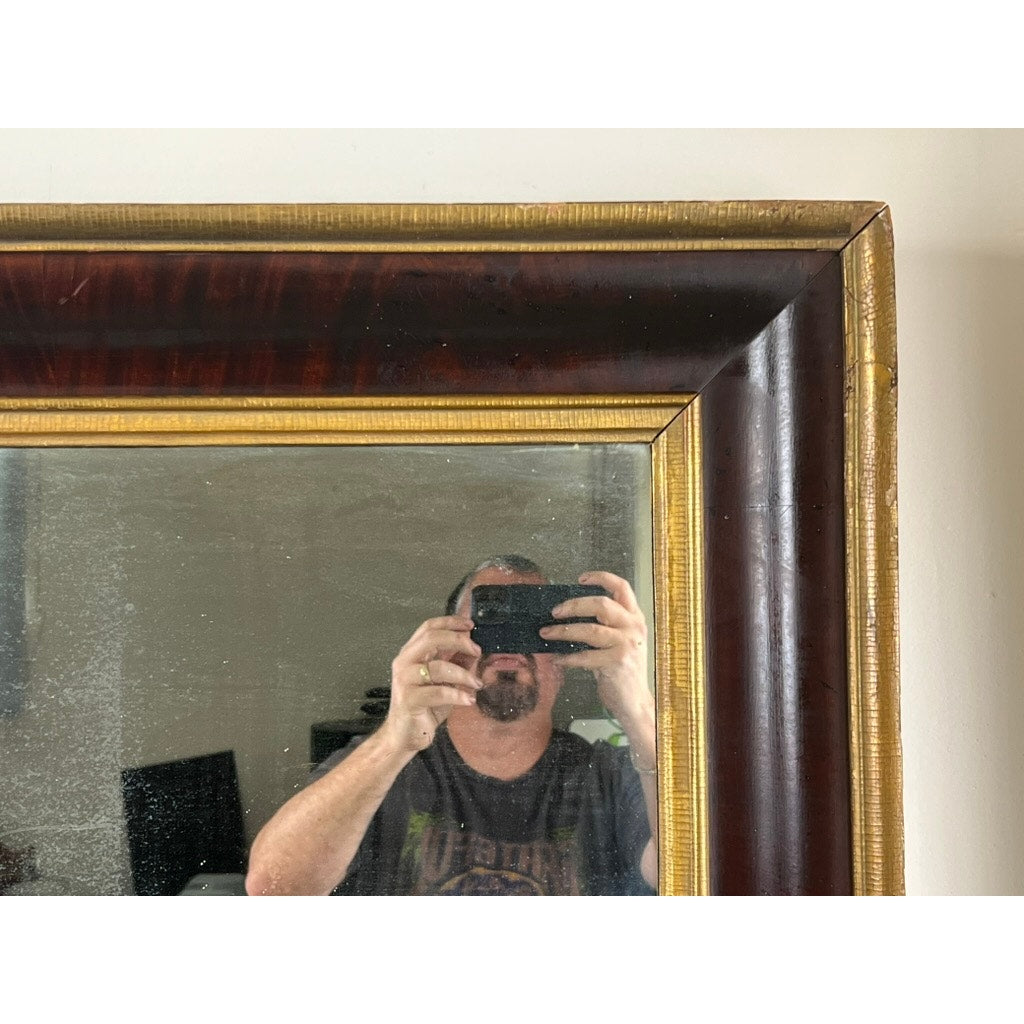 A person with short hair and a beard takes a selfie in an Antique American Empire Parcel Gilt Flame Mahogany Ogee Wall Mirror (mid-19th century), capturing part of the room reflected behind them.