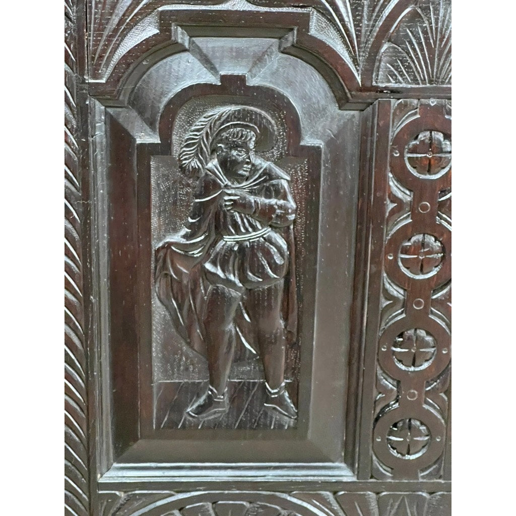 Carved wooden panel in Charles II style shows a person in historic dress holding a palm branch, set among ornate and geometric designs similar to those on an Antique 18th Century Charles II Style Mule Chest, maybe Irish or Scottish.
