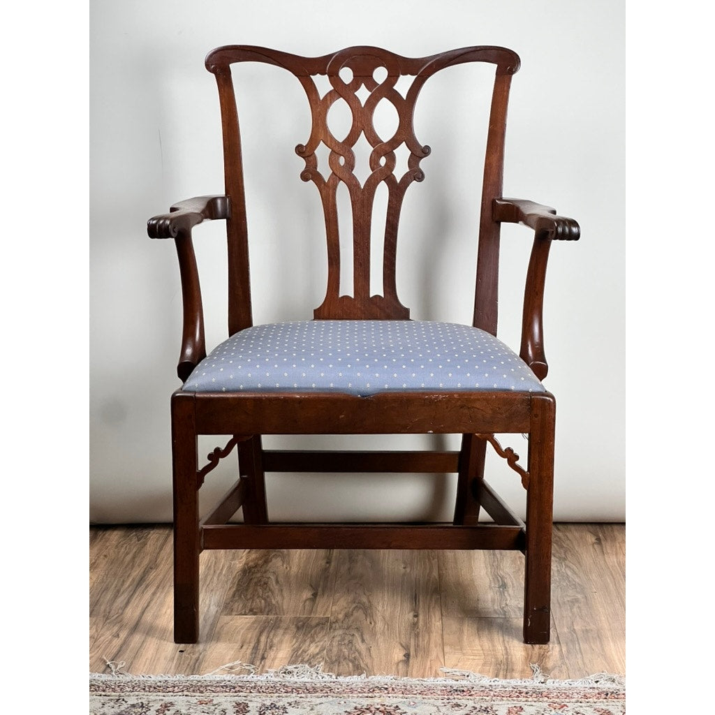 The Antique Chippendale Walnut Open Arm Chair, c. Late 18th Century, features an ornate carved backrest, curved arms, and a blue polka dot upholstered seat. This elegant piece sits on a wooden floor near a patterned rug. Brand: Unknown.