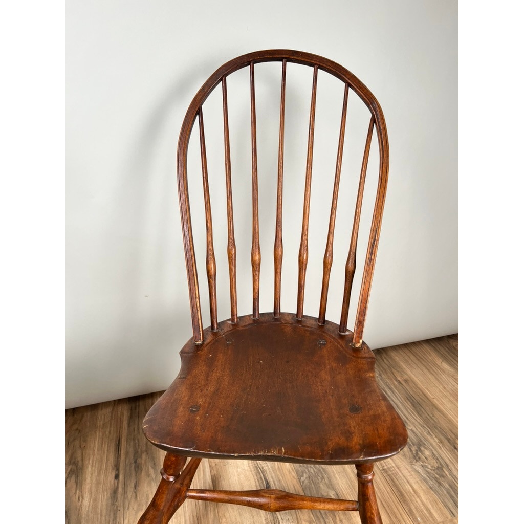 An Antique Near Pair of 18th Century Windsor Chairs with curved spindle backrests and flat seats sits on a wooden floor against a plain, light-colored wall. Brand: Unknown.