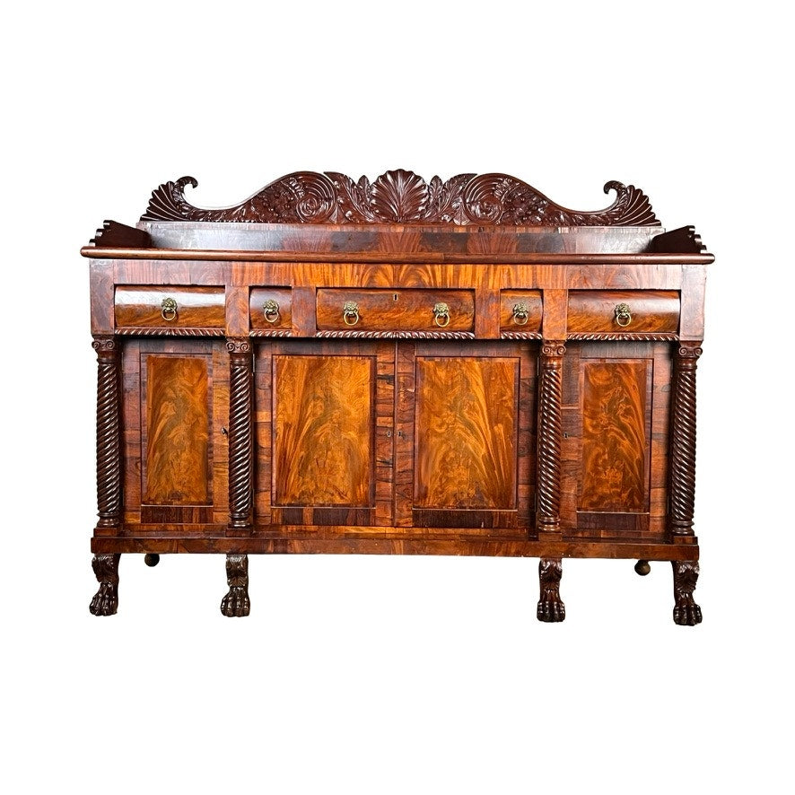 Antique American Empire Mahogany sideboard, likely Philadelphia c. 1840, with rosewood edge banding, carved details, four drawers and cabinet doors, twisted columns, claw feet, decorative back panel, brass handles, and rich swirling grain.
