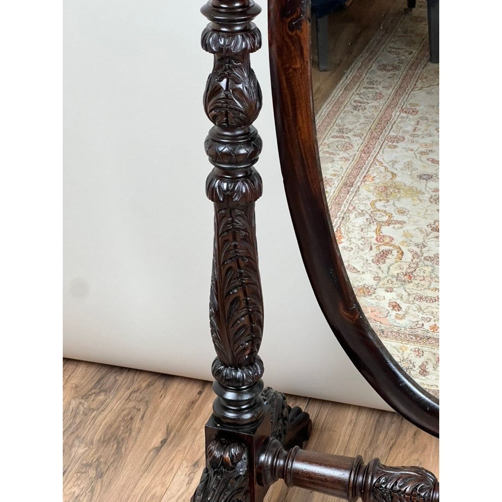 A close-up of the Impressive Antique American Empire Acanthus and Barbola Rose Carved Cheval Mirror c. 1840 reveals intricate leaf carvings, with part of the mirror frame and a patterned rug on a wooden floor in the background.