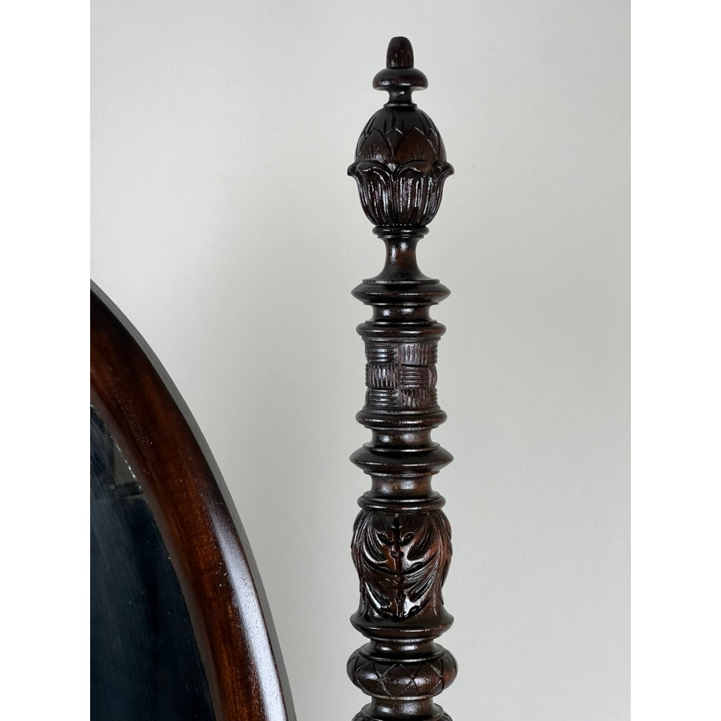 A close-up of the Impressive Antique American Empire Acanthus and Barbola Rose Carved Cheval Mirror c.1840 shows its ornately carved dark wood post with decorative patterns and finial, beside the mirror’s curved frame, set against a plain light background.
