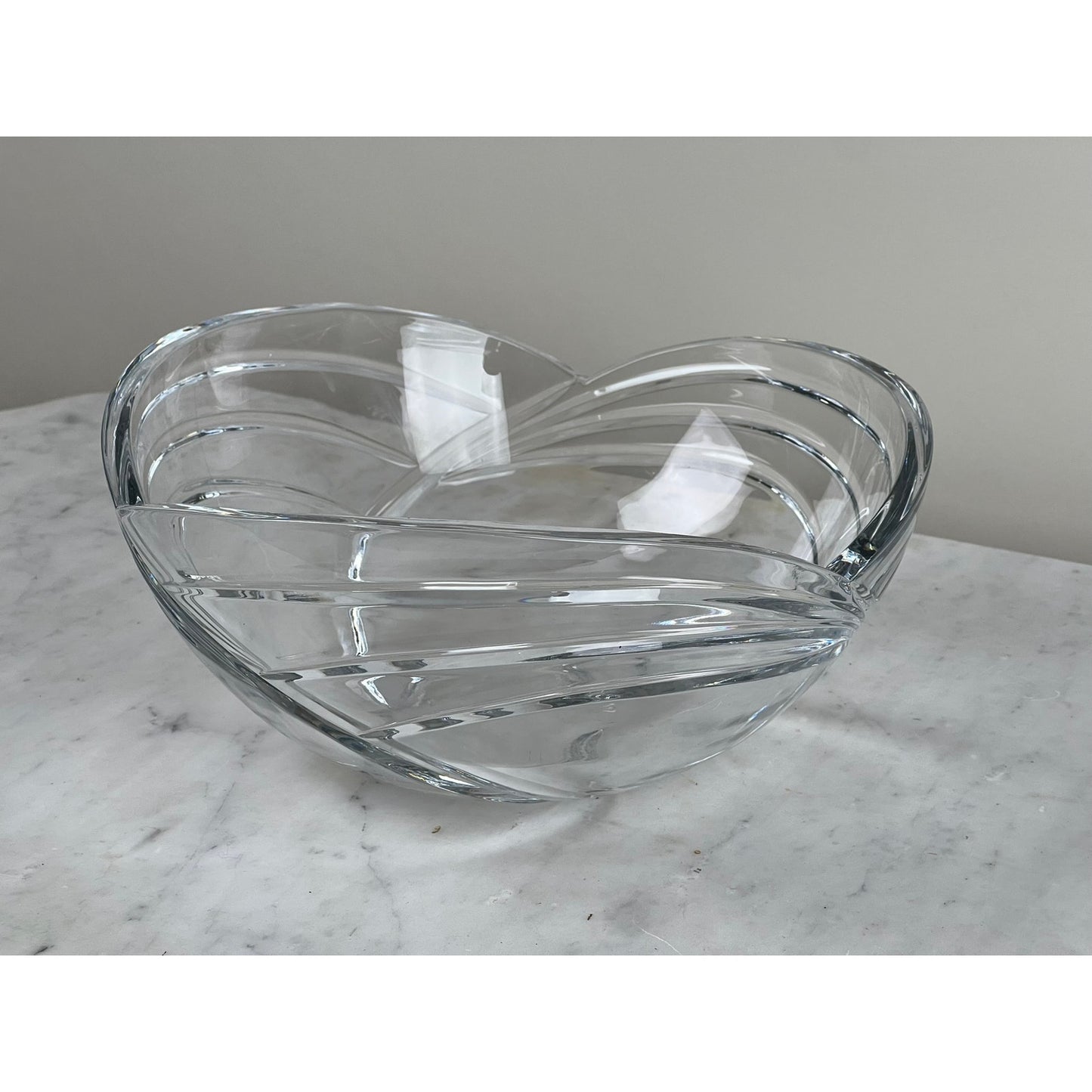 The Rogaska Samba Wave 10" Lead Crystal Bowl features elegant curved stripe patterns and sits on a white marble surface against a plain light gray background.