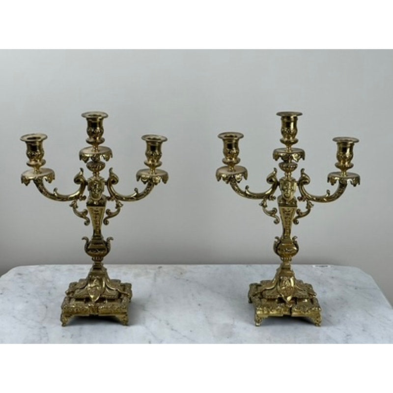 An Antique Pair Late 19th Century Brass Three Light Candelabra, each with ornate detailing and three candle holders, are displayed on a white marble surface—ideal for elegant Victorian-inspired decor accents.