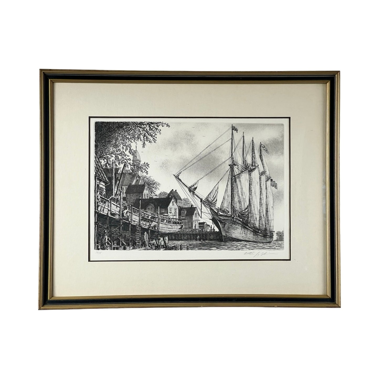 Framed Etching “The Schooner” by Alan Jay Gaines depicts a docked tall ship with sails furled, busy waterfront buildings, trees, and bustling figures working along the lively dock in the foreground.