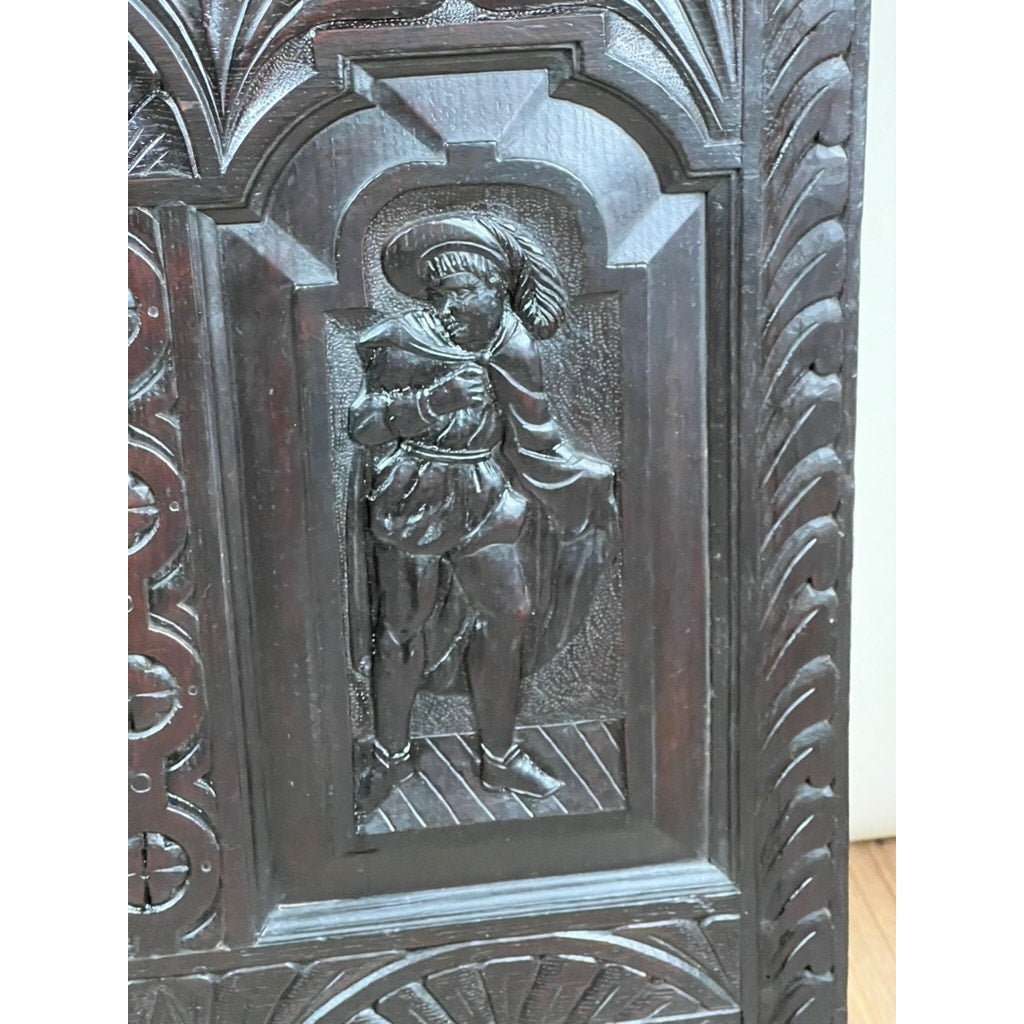 This antique 18th-century mule chest, likely Irish or Scottish, features a dark wood panel intricately carved in the Charles II style with a figure in period dress under an arched frame—a hallmark of 17th-century furniture craftsmanship.