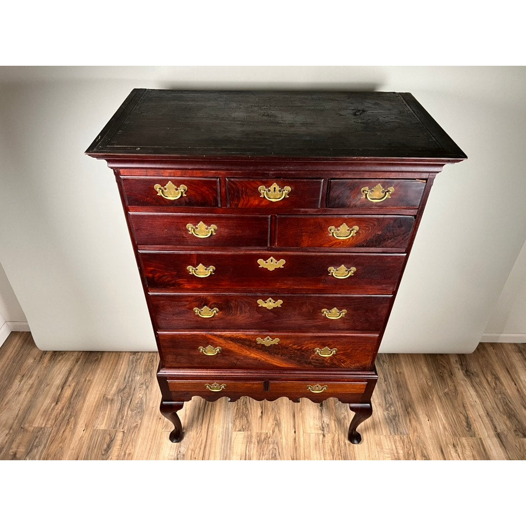 An Antique Queen Anne Walnut Chest on Frame with Drake Feet, probably Irish from the late 18th century, features multiple drawers with ornate brass handles and curved legs, standing on a wood floor against a white wall. Brand: Unknown.