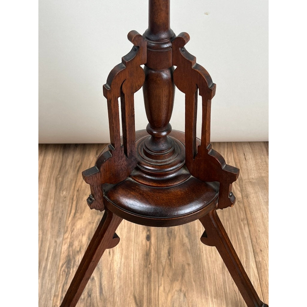 A close-up of the ornate carved wooden base on an Antique Victorian Walnut Candle Stand (Late 19th Century), featuring dark-stained walnut set against a light wood floor and plain background. Brand: Unknown.