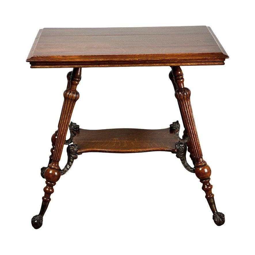 An Antique Victorian Oak Lamp Stand with bronze lions head mountings c. late 19th century, featuring a rectangular top, turned legs, ornate lower shelf, claw feet, intricate detailing, and a polished finish. Brand: Unknown.