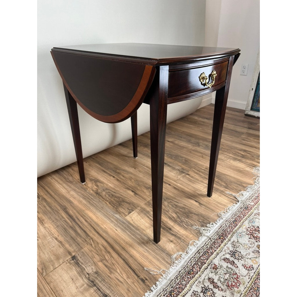 A Vintage Federal Style Edge Banded Mahogany End Table by Stickley sits on a wooden floor next to a patterned rug.