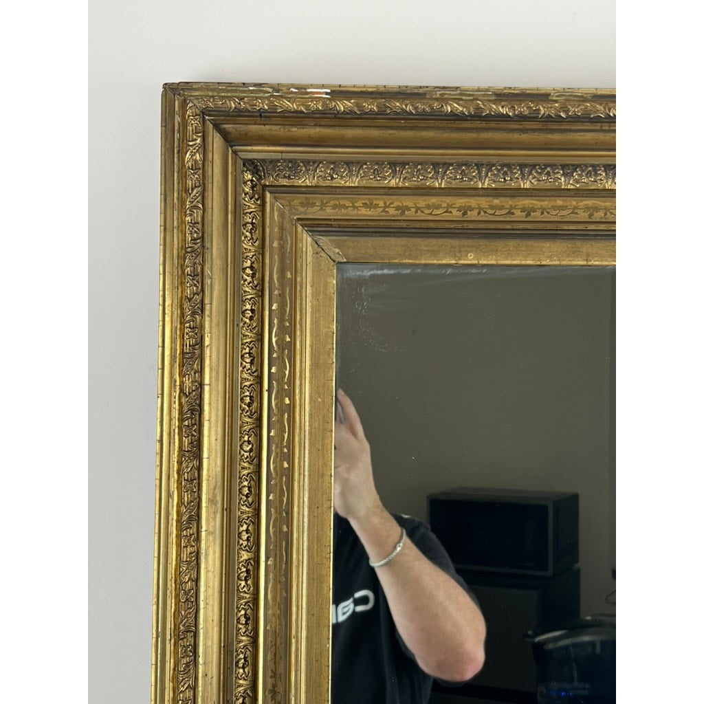 A close-up of a Fine Antique 19th Century Gilt Wood Mirror (39 x 34) captures part of a person's arm holding a phone, their face obscured by the ornate frame, with a TV and furniture visible in the background.