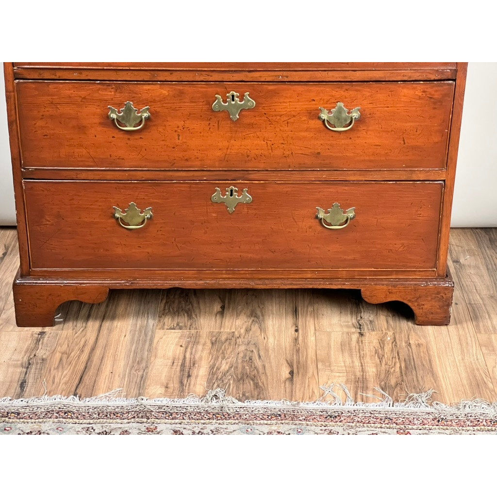 A close-up of the lower half of an Antique Chippendale Pine Graduated Four Drawer Chest (late 18th century, attr. Northampton MA maker) standing on a wood floor near the edge of an ornate rug. Brand: None/Unknown.