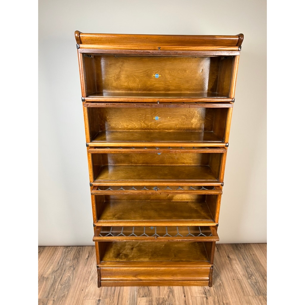 The Globe Wernicke Vintage Leaded Glass Five Stack Barrister Bookcase features five glass-front sections with metal pulls, and stands on a wooden floor against a plain light-colored wall.