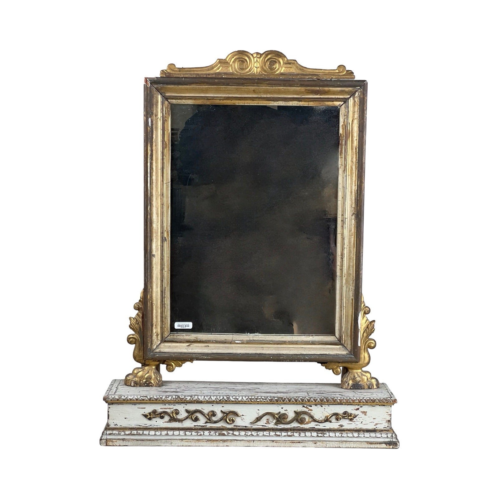 An Antique French Empire Gilt Wood Vanity/Table Mirror c. Mid 19th Century with an ornate gold frame, detailed side carvings, and a distressed white floral-accented base, shown against a plain white background. Brand unknown.