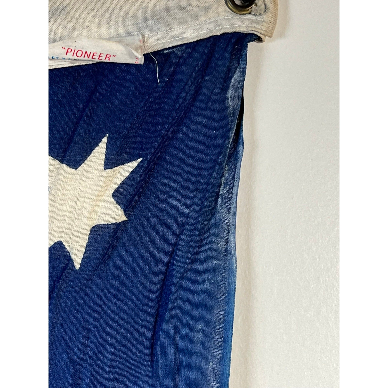 A close-up of a blue fabric with a white star, featuring the top edge of the Vintage Valley Forge “76” Bennington American Flag from the Bicentennial Era (c. 1976), and a metal grommet in the corner, powerfully evokes classic vintage Americana—calling to mind the authenticity of early Bennington and Valley Forge flags.