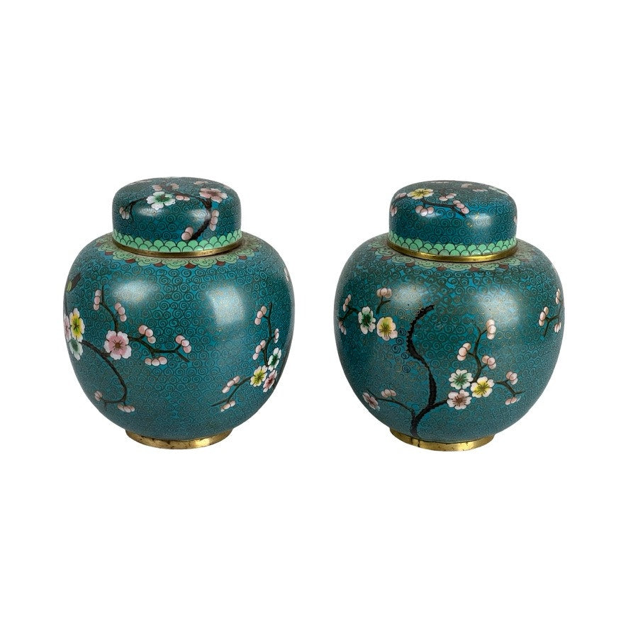 Vintage Pair of Chinese Cloisonné Ginger Jars—round, teal jars with lids, featuring floral and branch patterns in pink, white, and yellow, gold accents, an Asian-inspired design, and a decorative green band near the lid. Brand: Unknown.