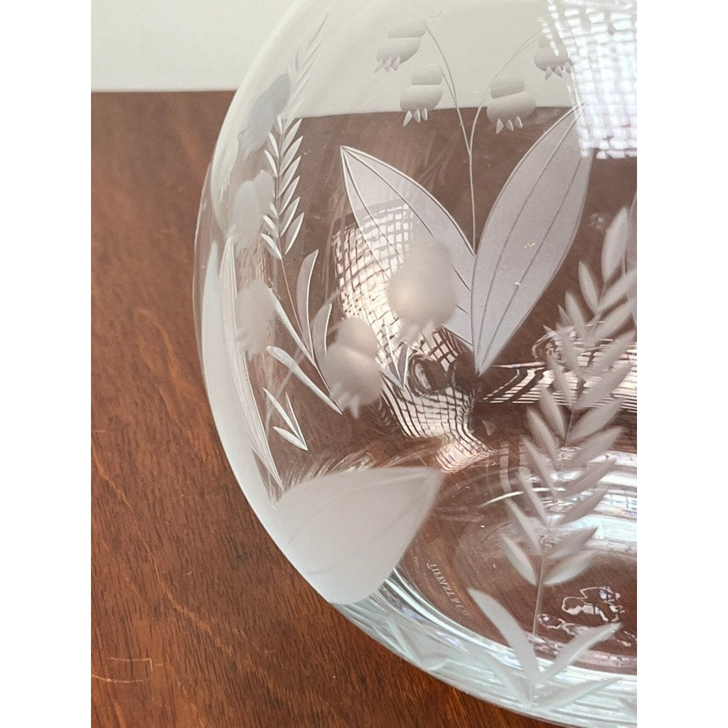 A close-up of the Vintage Tiffany & Co. Etched Crystal Pitcher, featuring a delicate lily of the valley floral motif on clear glass, with leaves and small berries visible as light reflects off the crystal.