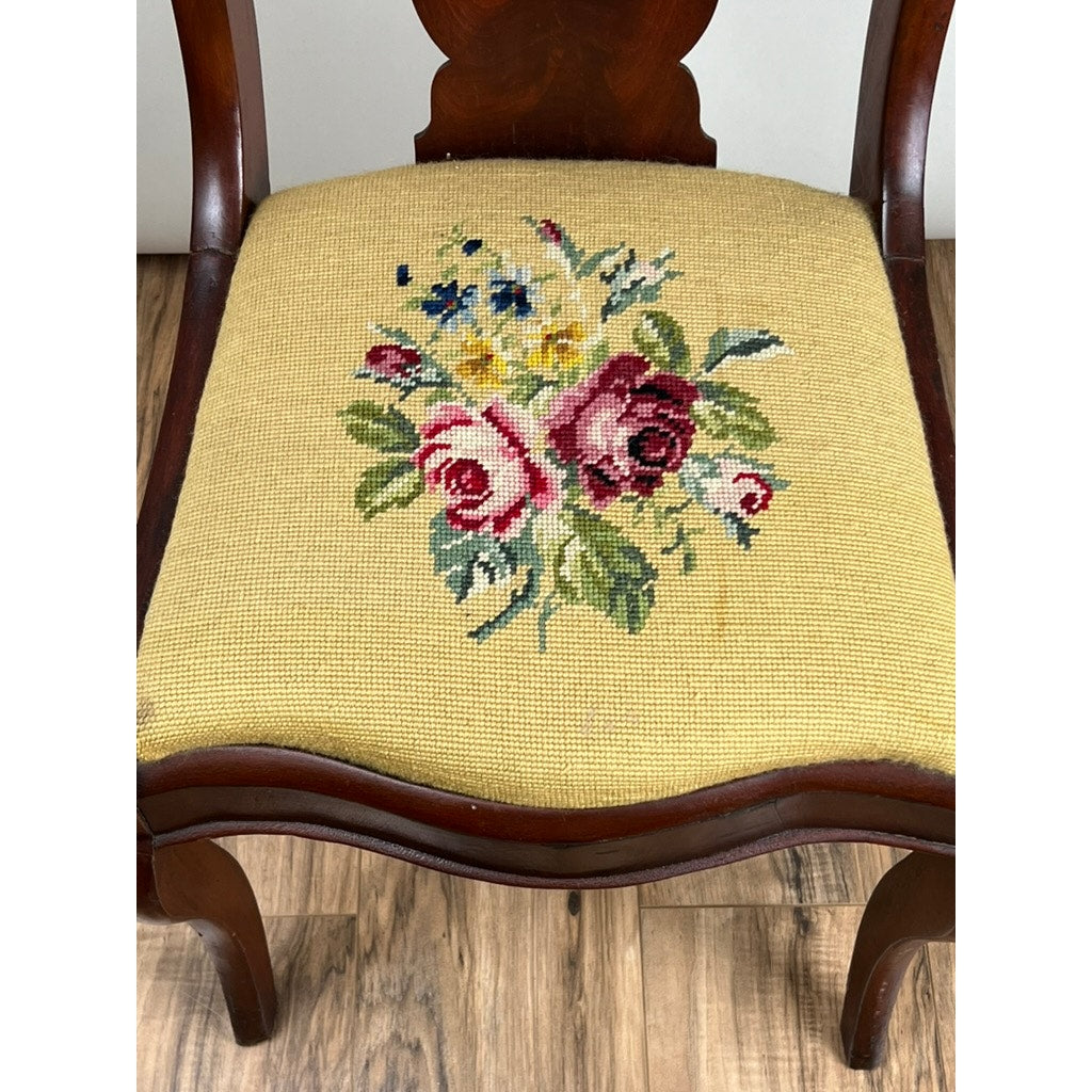 The Antique American Empire Flame Mahogany Saber Leg Side Chair (c. Mid 19th Century) features antique needlepoint upholstery with a beige seat and red, pink, and yellow floral patterns, elegantly displayed on a wooden floor.
