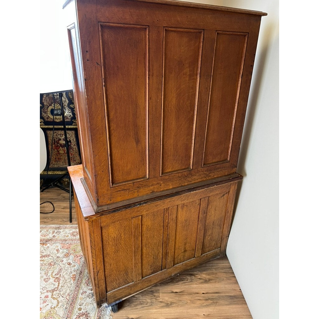 An Antique Early 20th Century Oak Multidrawer File with Roll Top Pigeon Hole Top stands on a wooden floor by a patterned rug, its rich brown paneled sides complementing nearby decorative furnishings. Brand: Unknown.