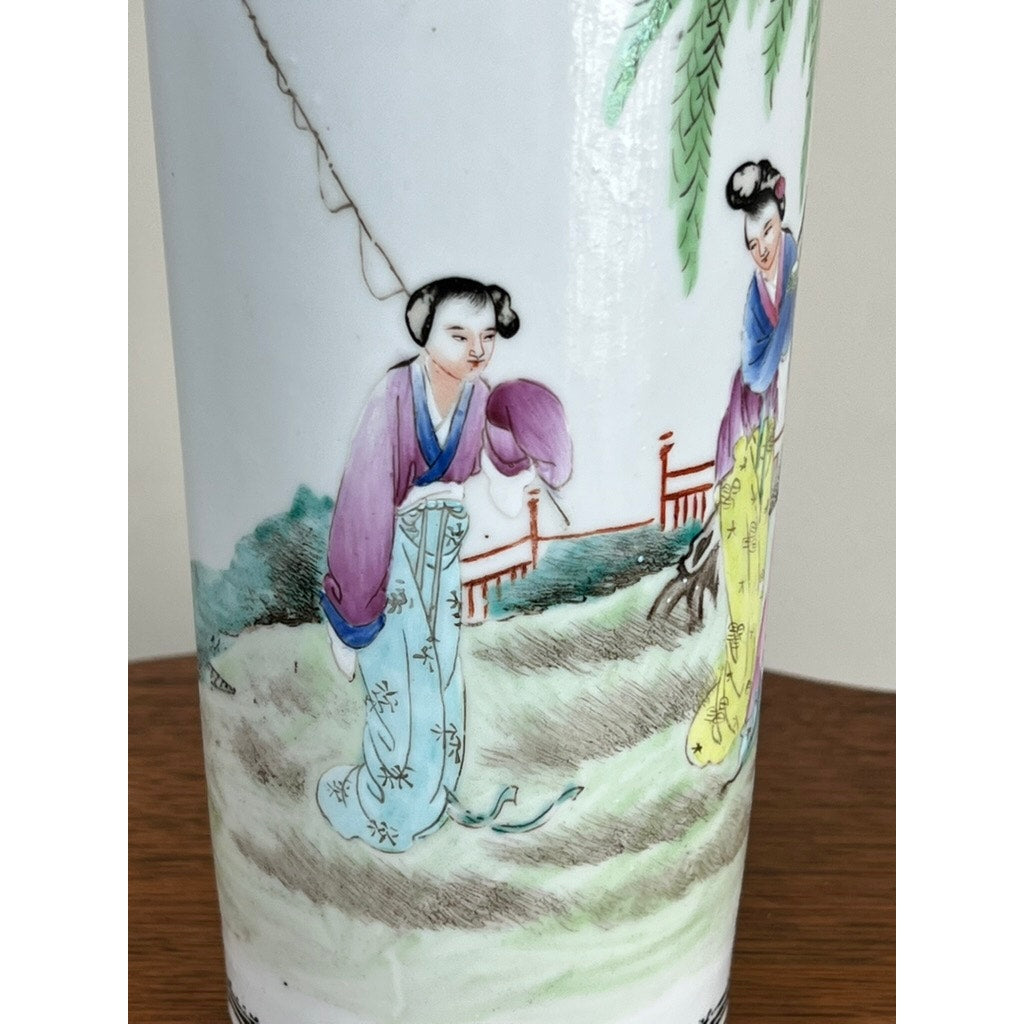 Detail from an Antique Qing Dynasty Famille Rose 12” Vase with Qianlong Mark, showing two women in traditional dress by a fence amid trees and greenery. Their colorful robes are richly painted. Brand: Unknown.