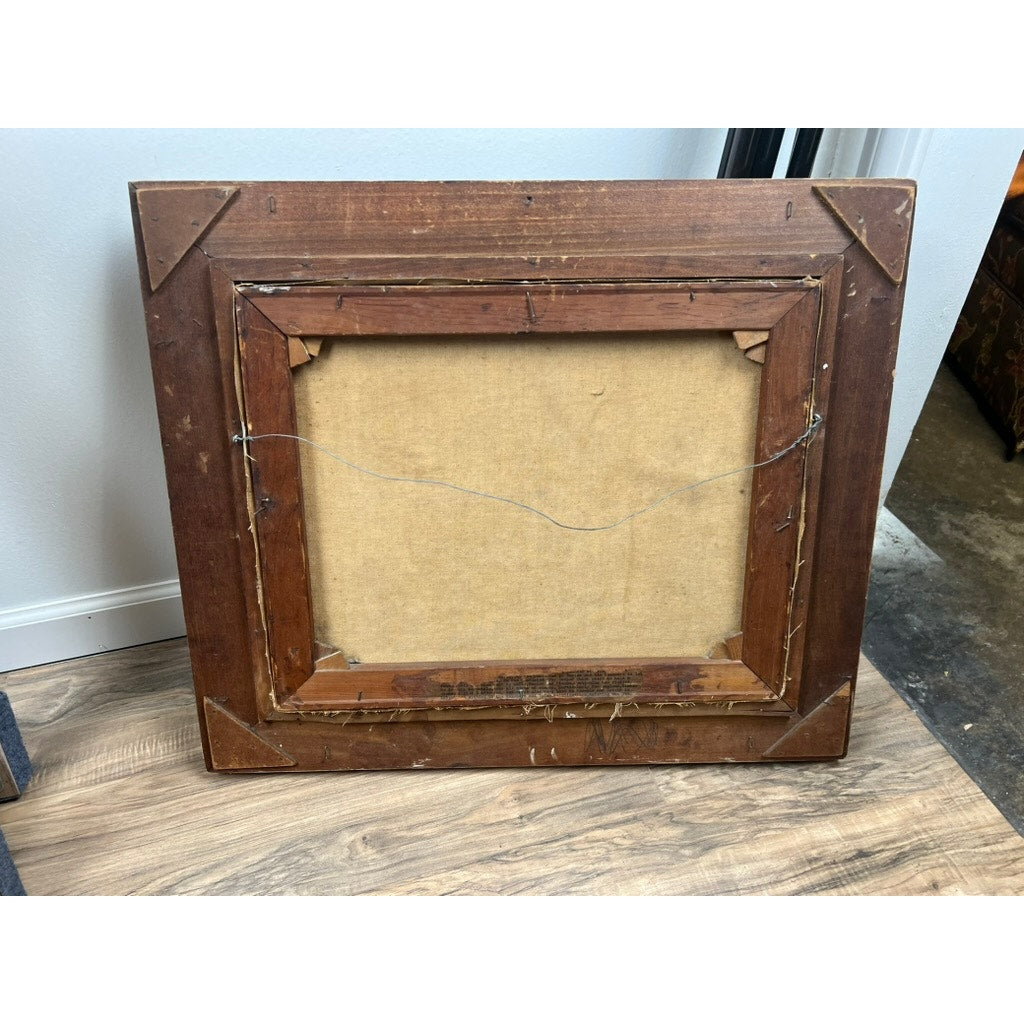 The back of the vintage oil painting “Two Ships Off the Beach” (signed lower left) is shown, revealing its canvas and hanging wire. The wooden frame has visible wear with scratches, and it’s resting on a wood floor against a white wall.
