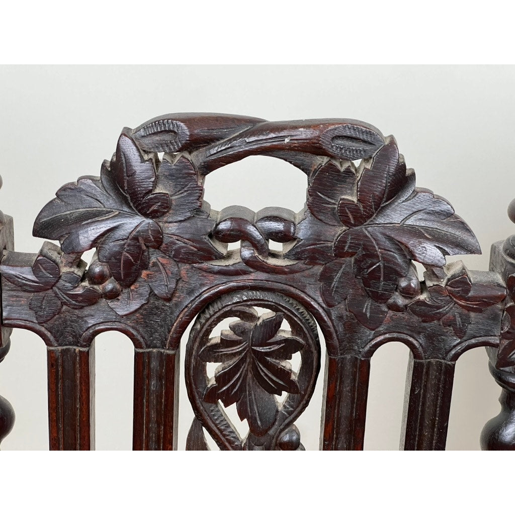 Pair of antique French walnut hunting chairs, late 19th century, with intricately carved backs featuring two birds among leaves and berries, a curved top rail, and vertical slats below. Brand unknown.