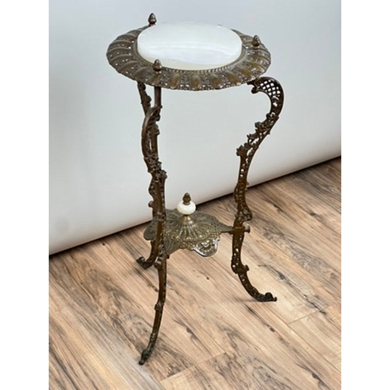 An Antique Victorian Bronze and Onyx Stand (late 19th century) with ornate scrollwork legs and a round white onyx top, displayed on a wood-patterned floor against a plain white wall. Brand: Unknown.