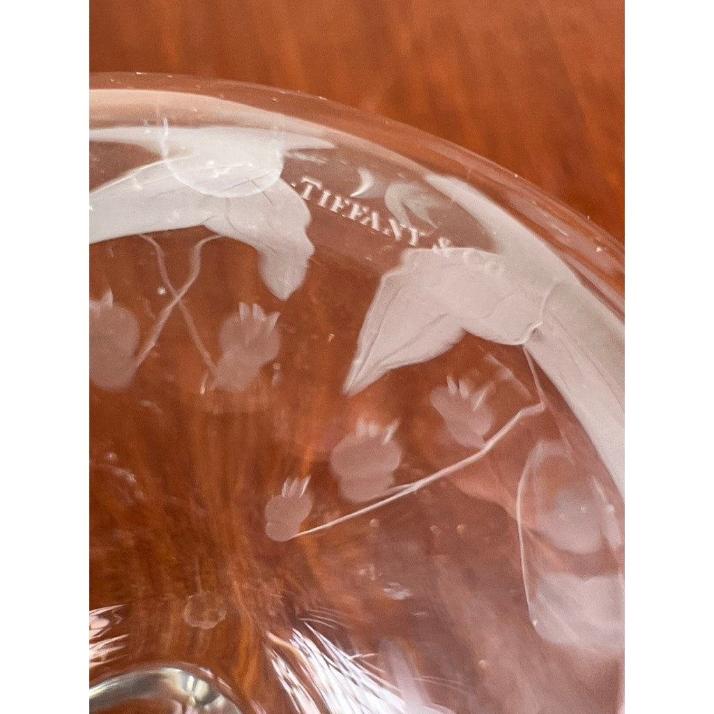 Close-up of a Vintage Tiffany & Co. Etched Crystal Pitcher, featuring a delicate lily of the valley motif and TIFFANY & CO. engraved near the rim, set against a wooden background.