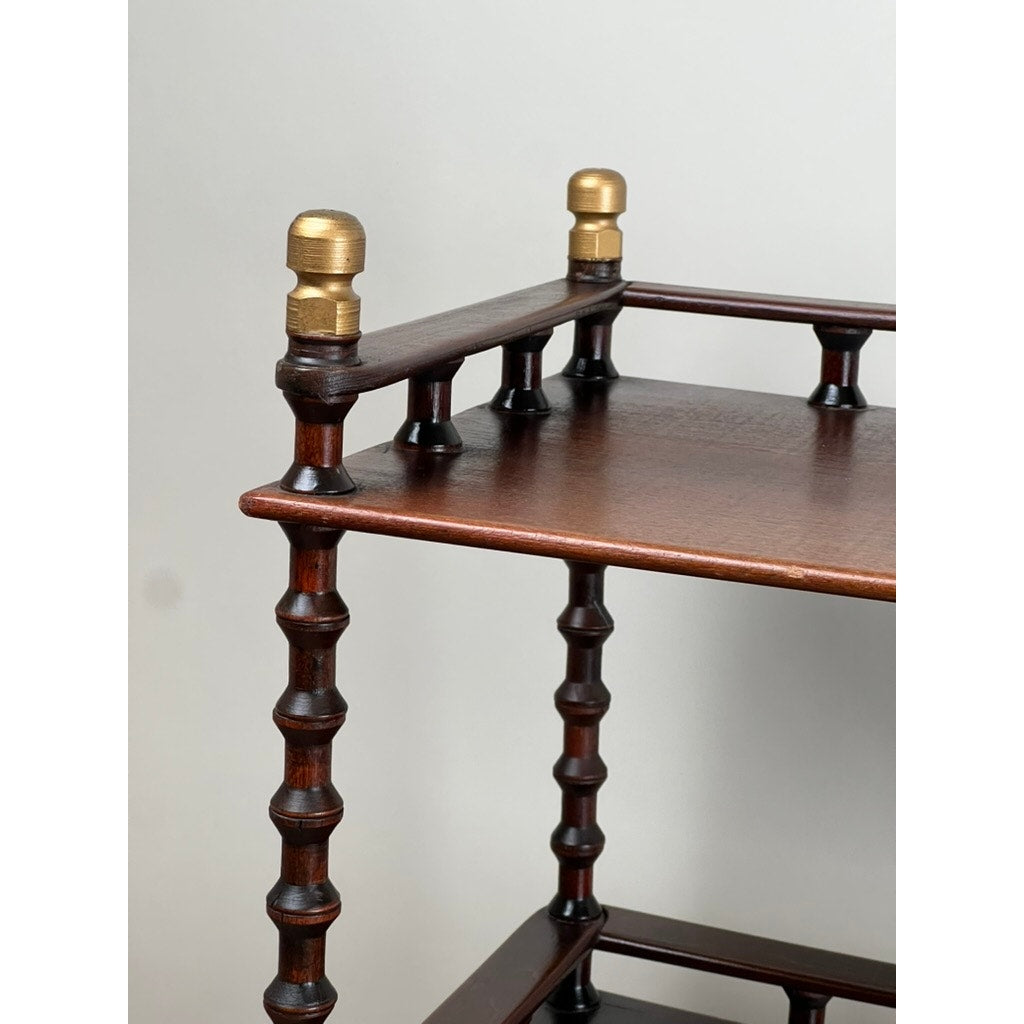 A close-up of a Vintage Bobbin-turned, Three Shelf Wooden étagère or Whatnot with bobbin-turned legs and brass fittings on the top corners, set against a plain light background. Brand: None/Unknown.