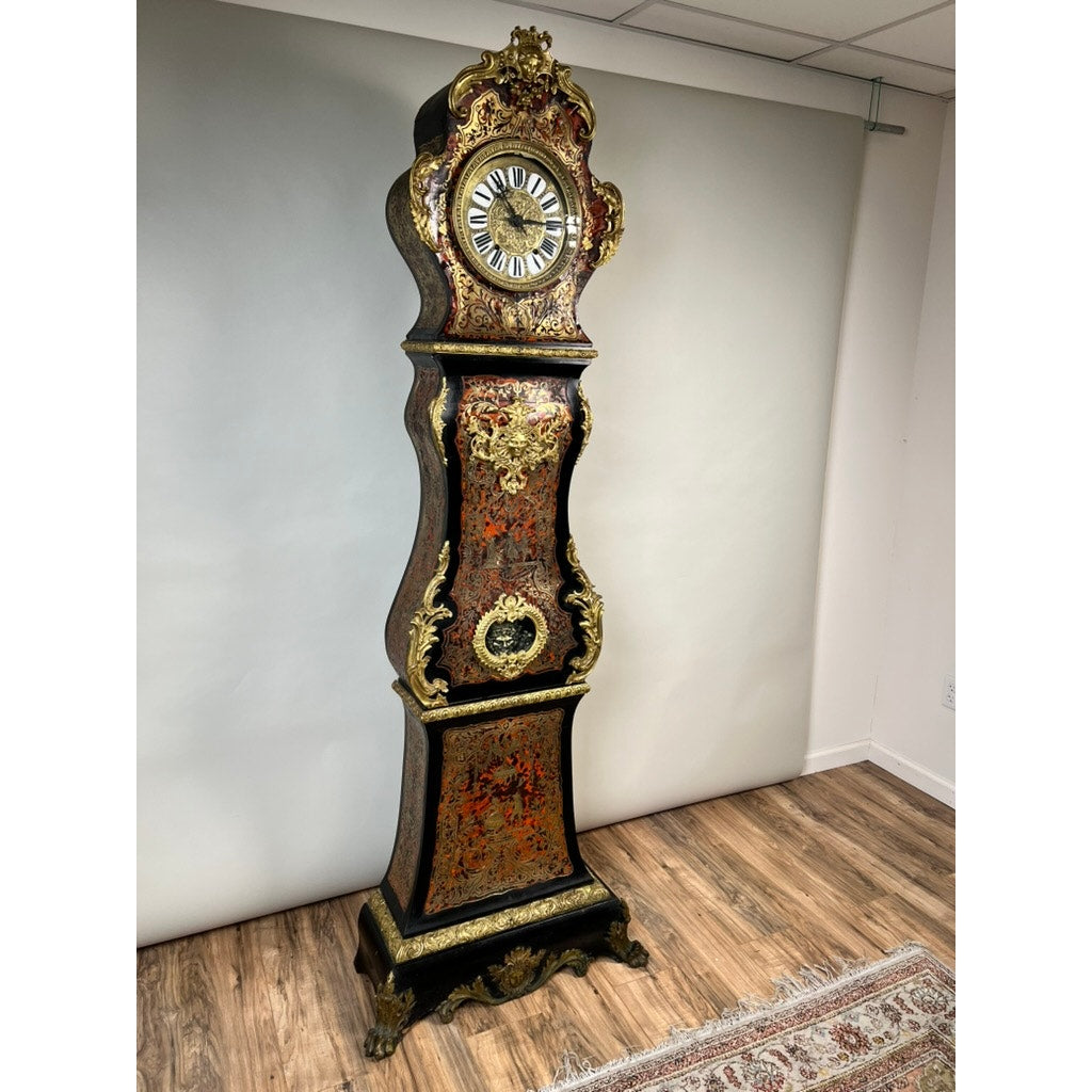 Monumental French Napoleon III Boulle Marquetry Floor Clock with Ormolu Mounts, dating from circa 1865–1885, featuring gold and red floral detailing, intricate black accents, decorative gilded trim, and exquisite marquetry craftsmanship—a striking testament to French decorative artistry—stands on a wooden floor against a plain white wall.