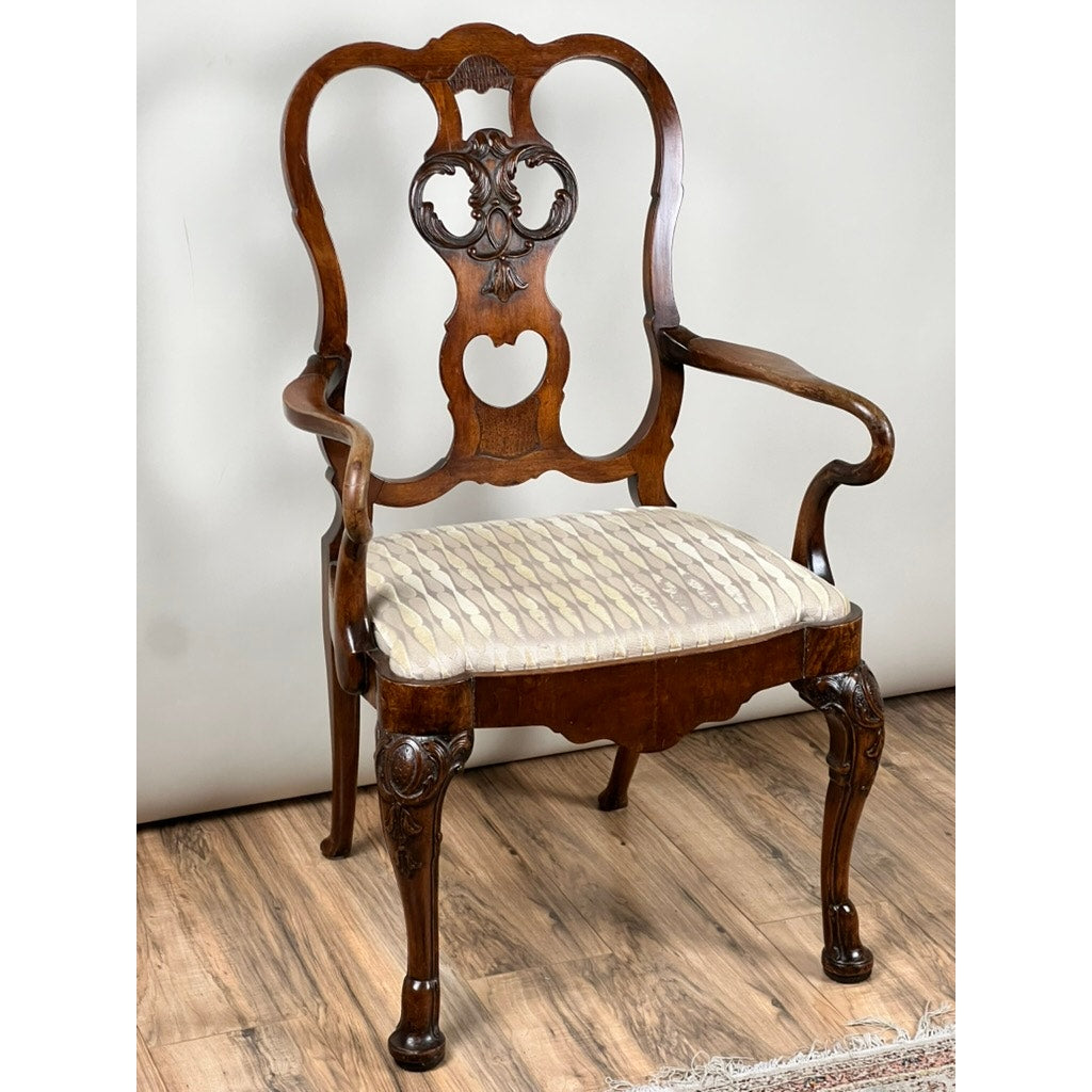 An Antique George III Mahogany Open Arm Chair (late 18th century) features an ornate carved backrest, curved arms, cabriole legs, and a cushioned seat in light patterned fabric, shown on a wooden floor against a plain wall.