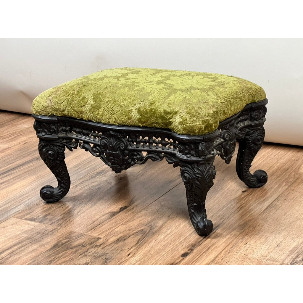 Antique Victorian Cast Iron Foot Stool c. 1900 with ornate cast iron legs and a green textured cushion, displayed on wood flooring against a white background—a collectible gem for decorative arts enthusiasts. Brand: Unknown.