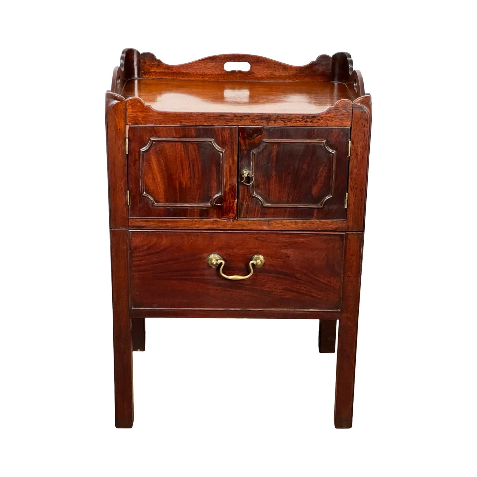 An Antique George III Bedside Commode from the late 18th century, featuring a pull-out leather surface, high back, two geometric cabinet doors, a brass-handled lower drawer, and four straight legs. Brand unknown.