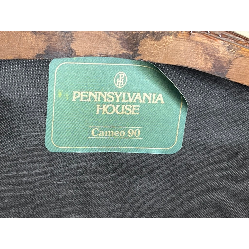 A green and gold label with "PENNSYLVANIA HOUSE" and "Cameo 90" is attached to dark fabric on a Vintage Louis XV Style Fauteuil Arm Chair by Pennsylvania House, partially under a wooden edge.