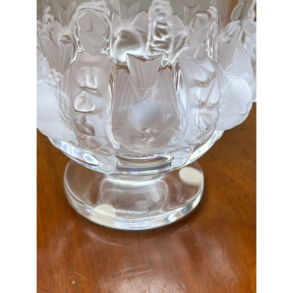 A close-up of the base and lower part of a Vintage Lalique Dampierre Sparrow Footed Vase by Lalique, featuring frosted sparrow and floral patterns, displayed on a polished wooden surface.