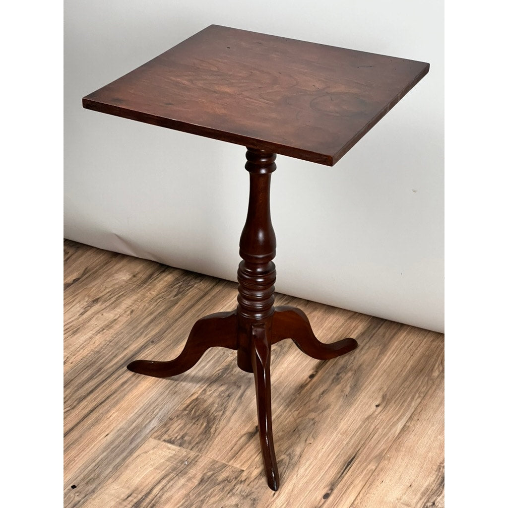 Antique Low Cherry Candle Stand, c. mid-19th century, with a square top, turned central column, and three curved legs. Unbranded piece displayed on a wood floor against a plain white wall.