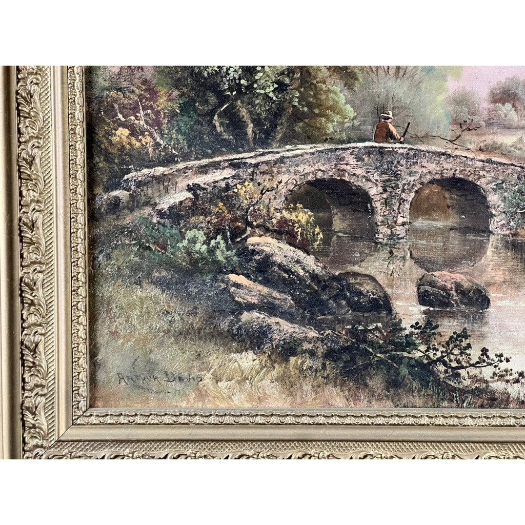 A close-up of the Antique Early 20th Century Oil on Canvas Painting “Spectacle Bridge” signed Arthur Davis lower left shows an old stone bridge over a river, lush greenery, and a person in a hat with a walking stick in an ornate frame.